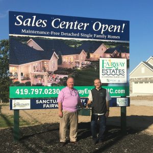 Thomas Bohlander and Tony Corona standing in front of an Epcon franchise sign reading "Sales Center Open!"