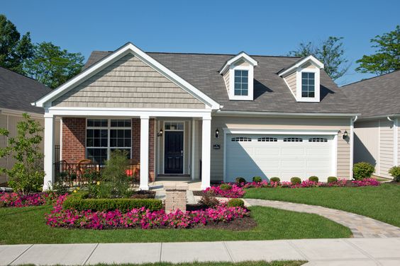 A one-story home features a front yard landscaped with fuchsia flowers and low bushes.