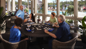 Residents socialize and play games on the screened-in patio of an Epcon clubhouse.